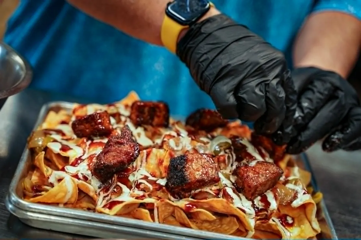 a person wearing black gloves putting food on a tray