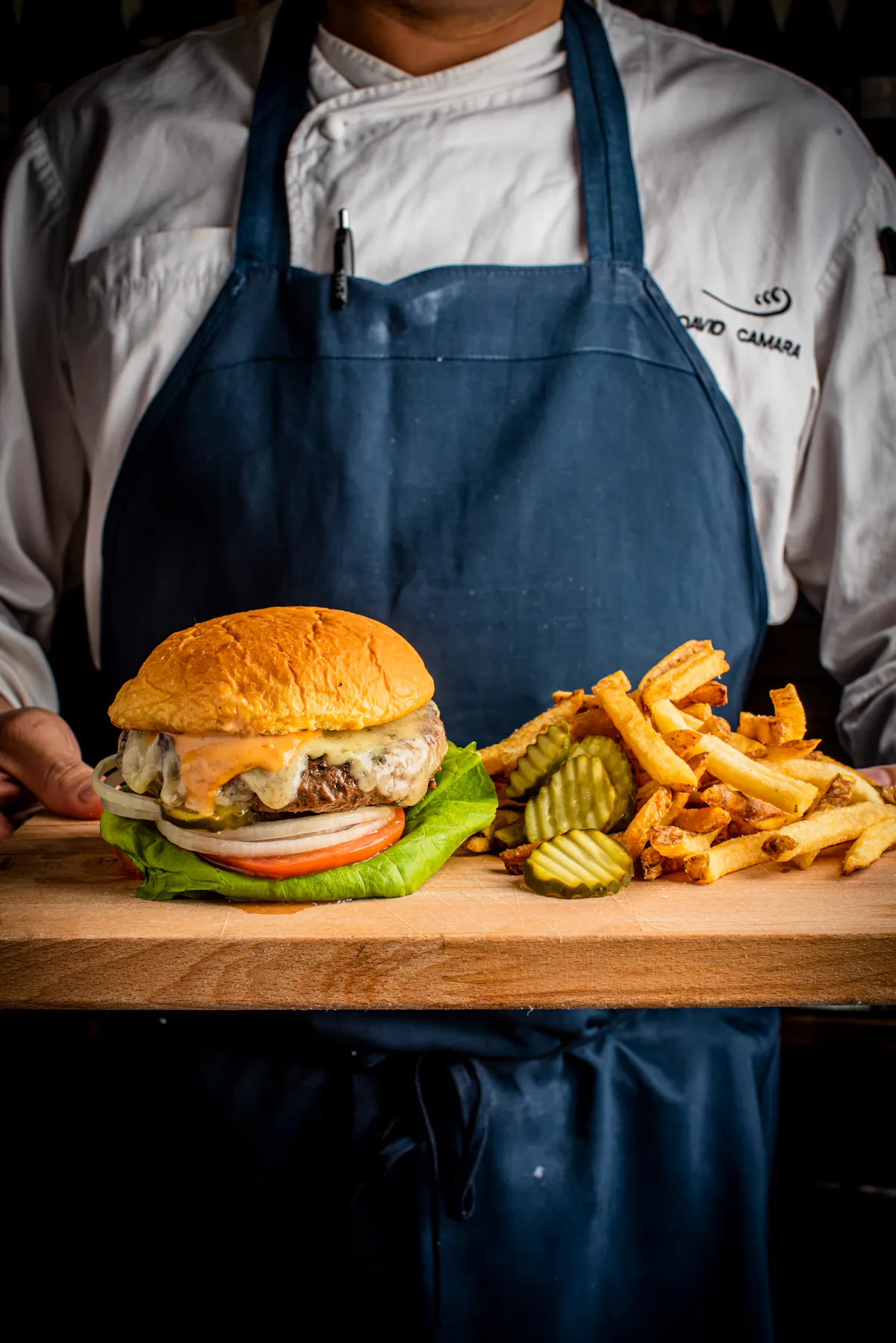 a person sitting at a table with a sandwich and fries