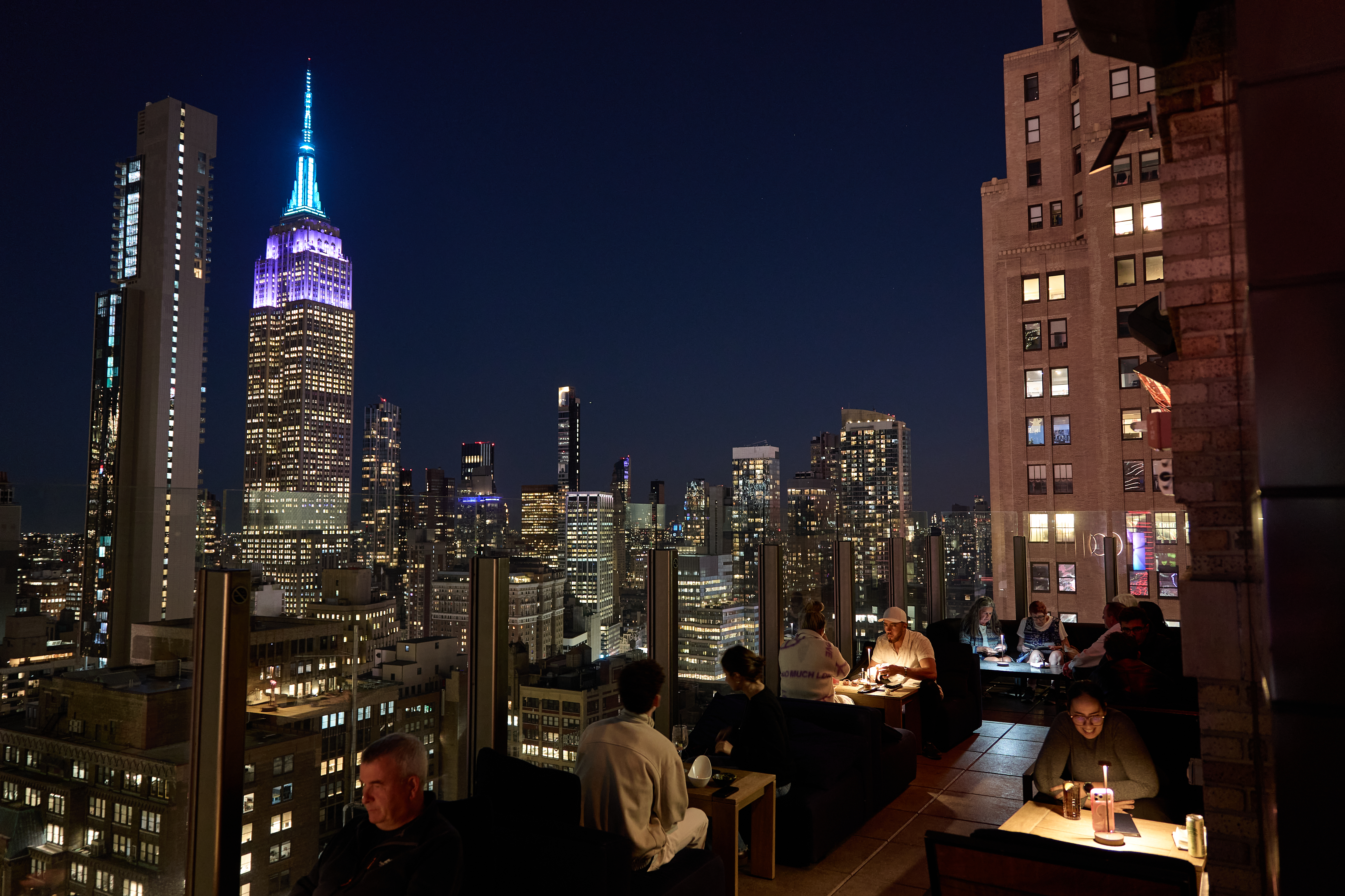 a group of people sitting at tables with a city skyline in the background