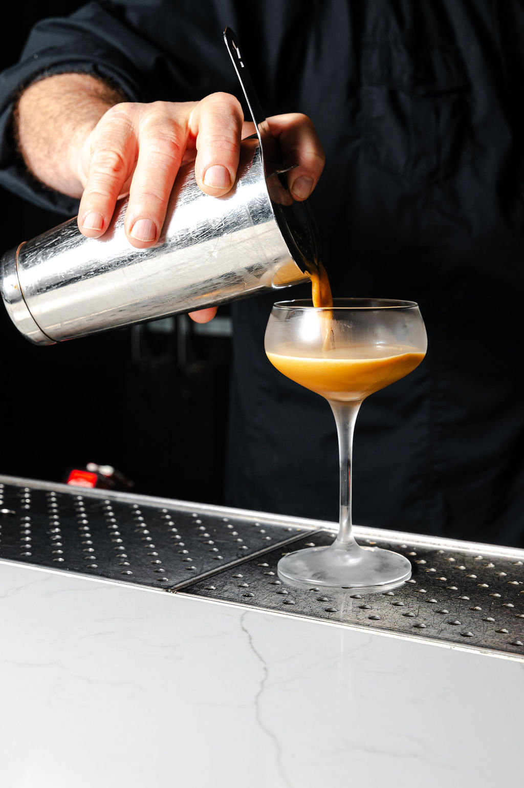 a person pouring liquid into a glass