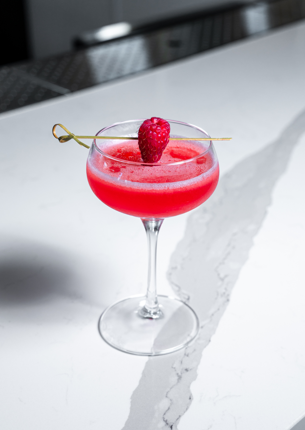 a glass with a drink and a raspberry on it