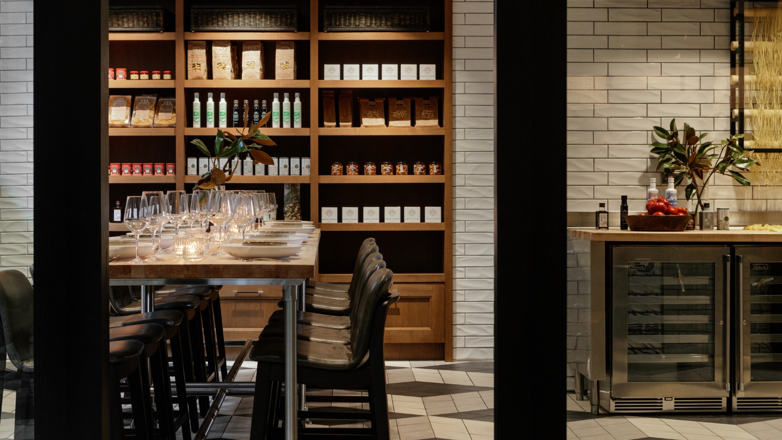 a table with wine glasses and chairs in a room with shelves of liquor