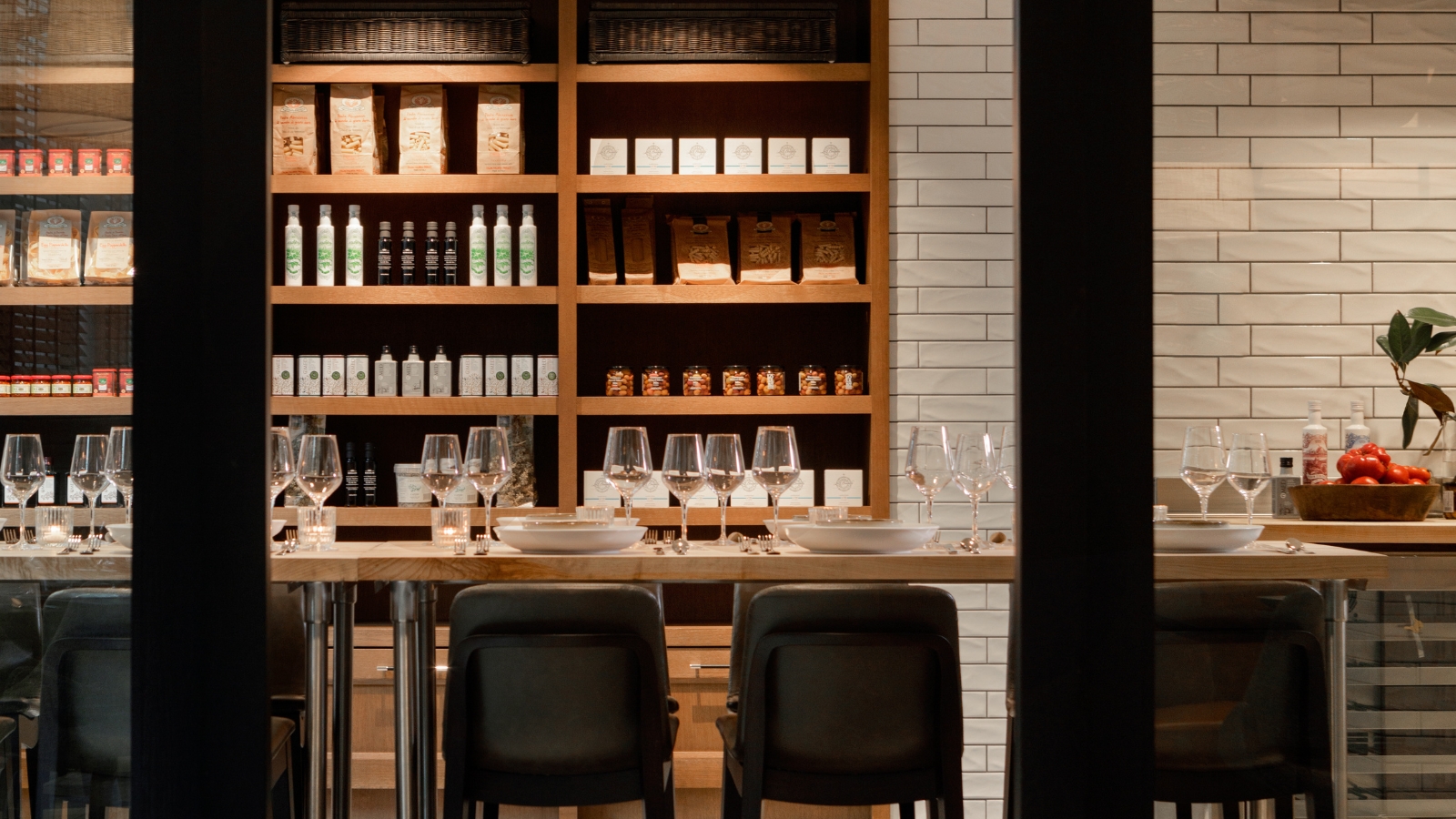 a table with wine glasses and chairs in front of shelves