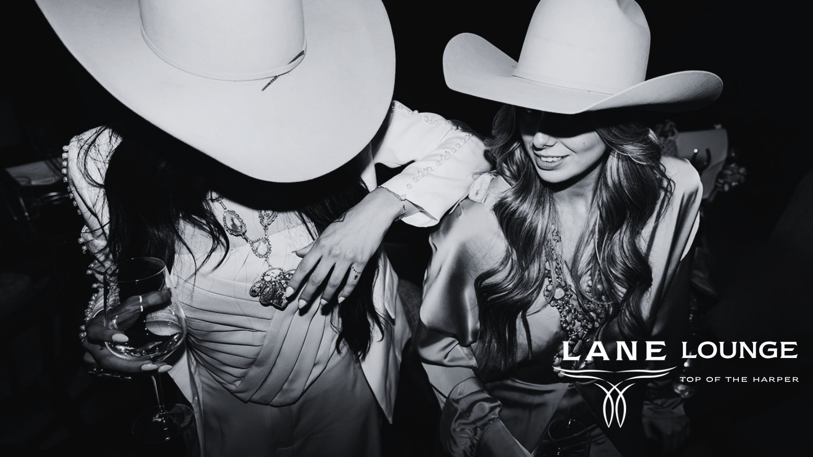 Two guests in white cowboy hats holding drinks, featuring Lane Lounge at The Harper branding.