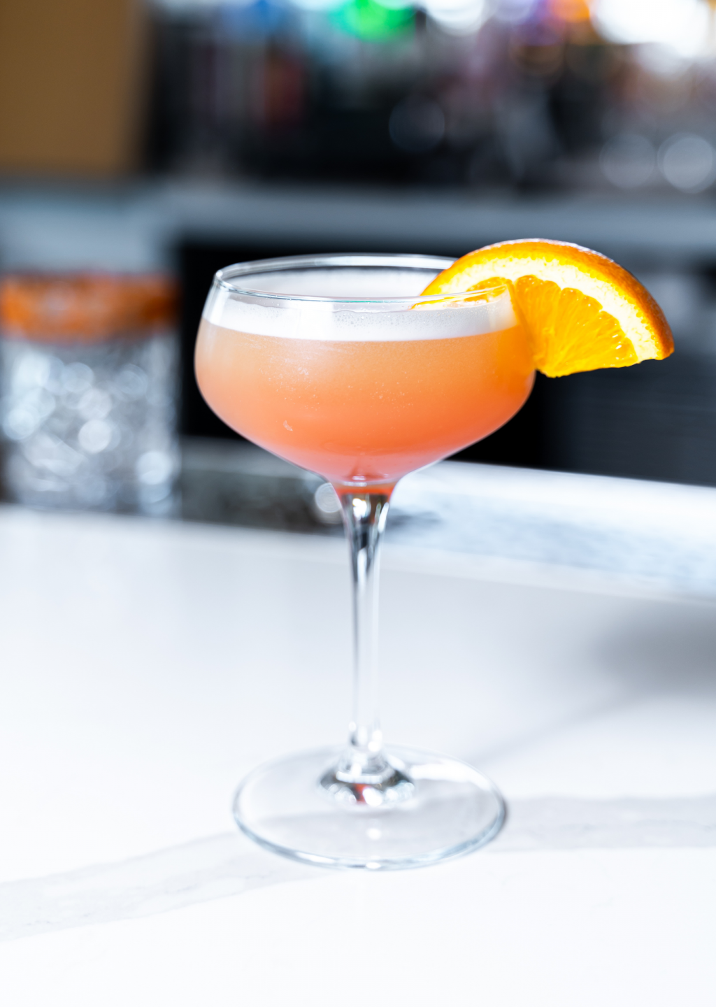 a glass with a drink and a slice of orange on it