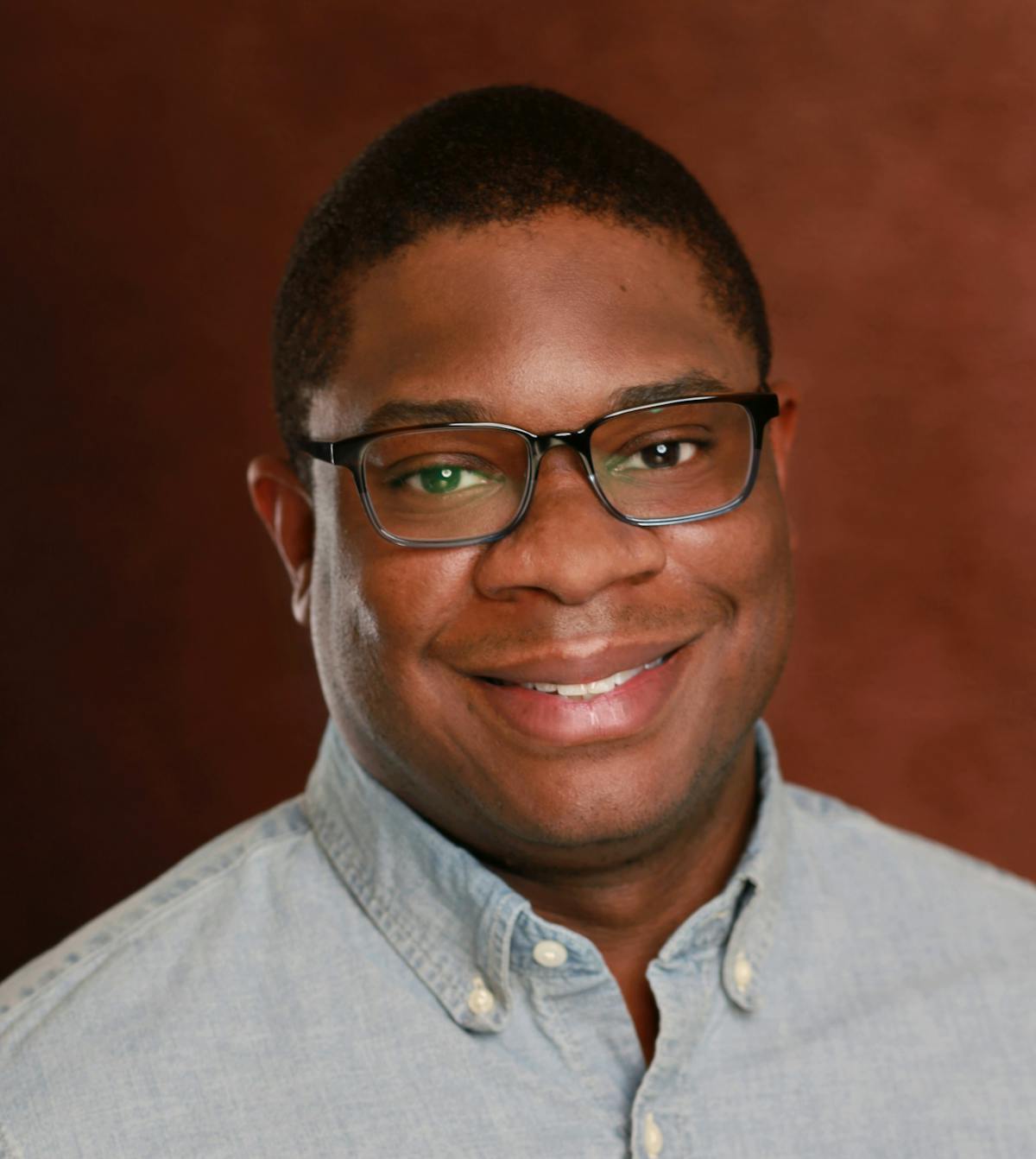 a man wearing glasses and smiling at the camera