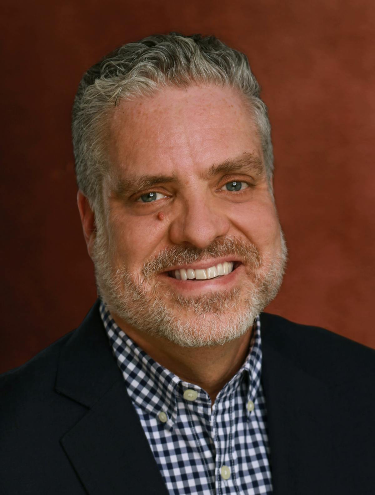 a man wearing a suit and tie smiling and looking at the camera