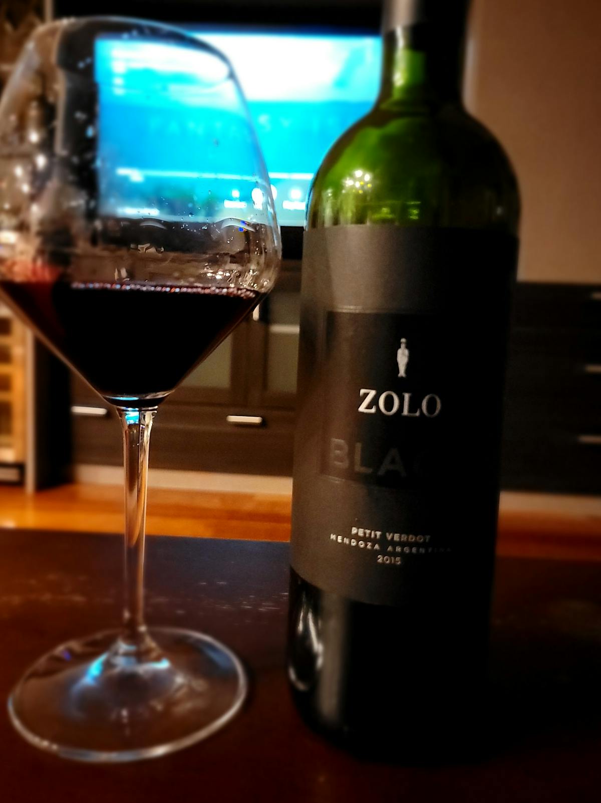a close up of a bottle and a glass of zolo black petit verdot wine