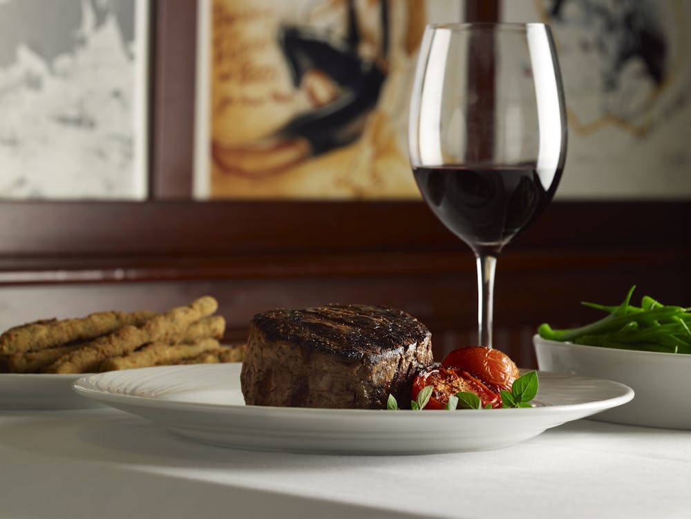 a close up of a plate of food and a glass of wine