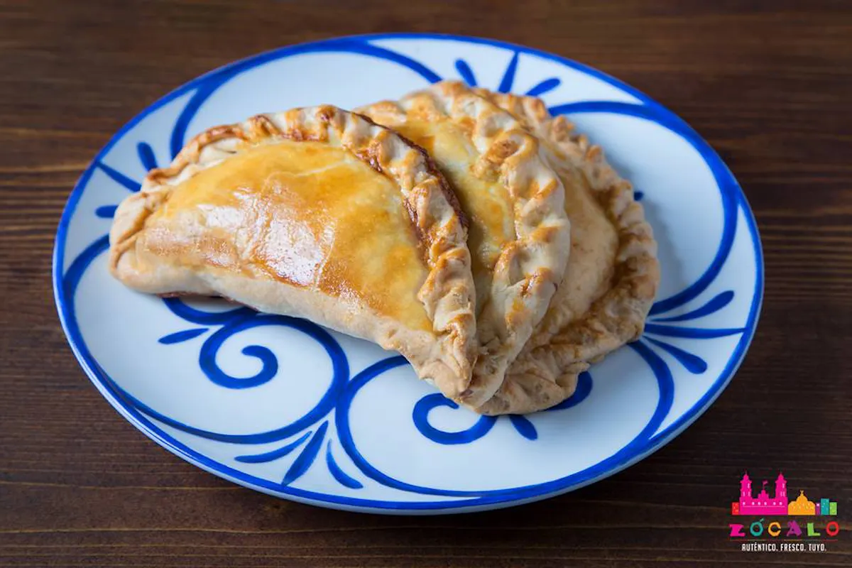 2 empanadas sitting on a blue and white plate