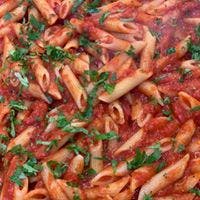 a close up of pasta in red sauce topped with cilantro