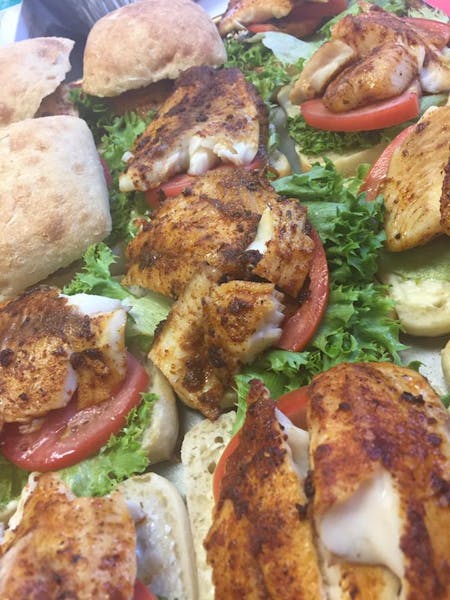 a close up of a stack of grilled chicken breast, lettuce, and sliced tomato