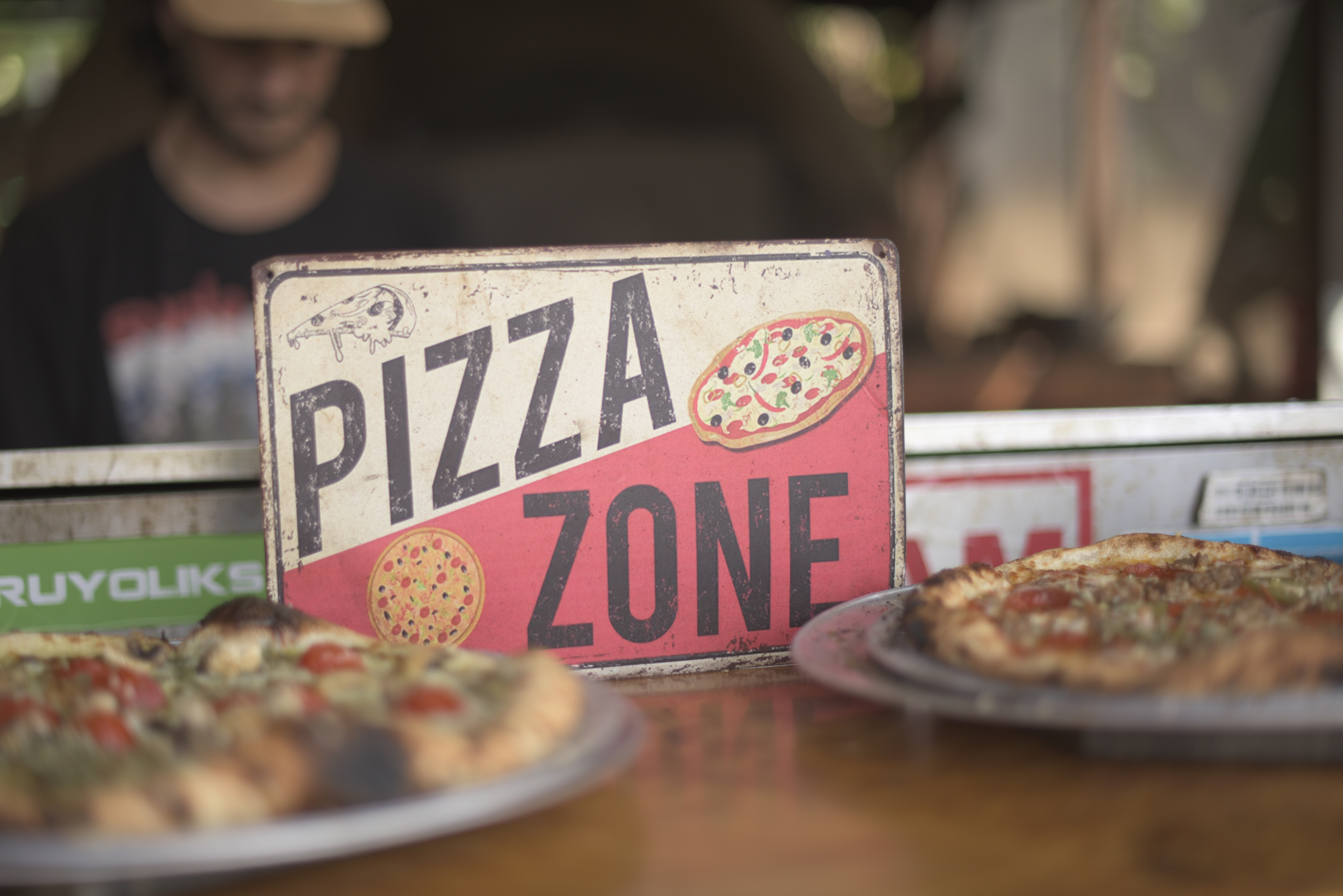 a sign on a table with pizzas