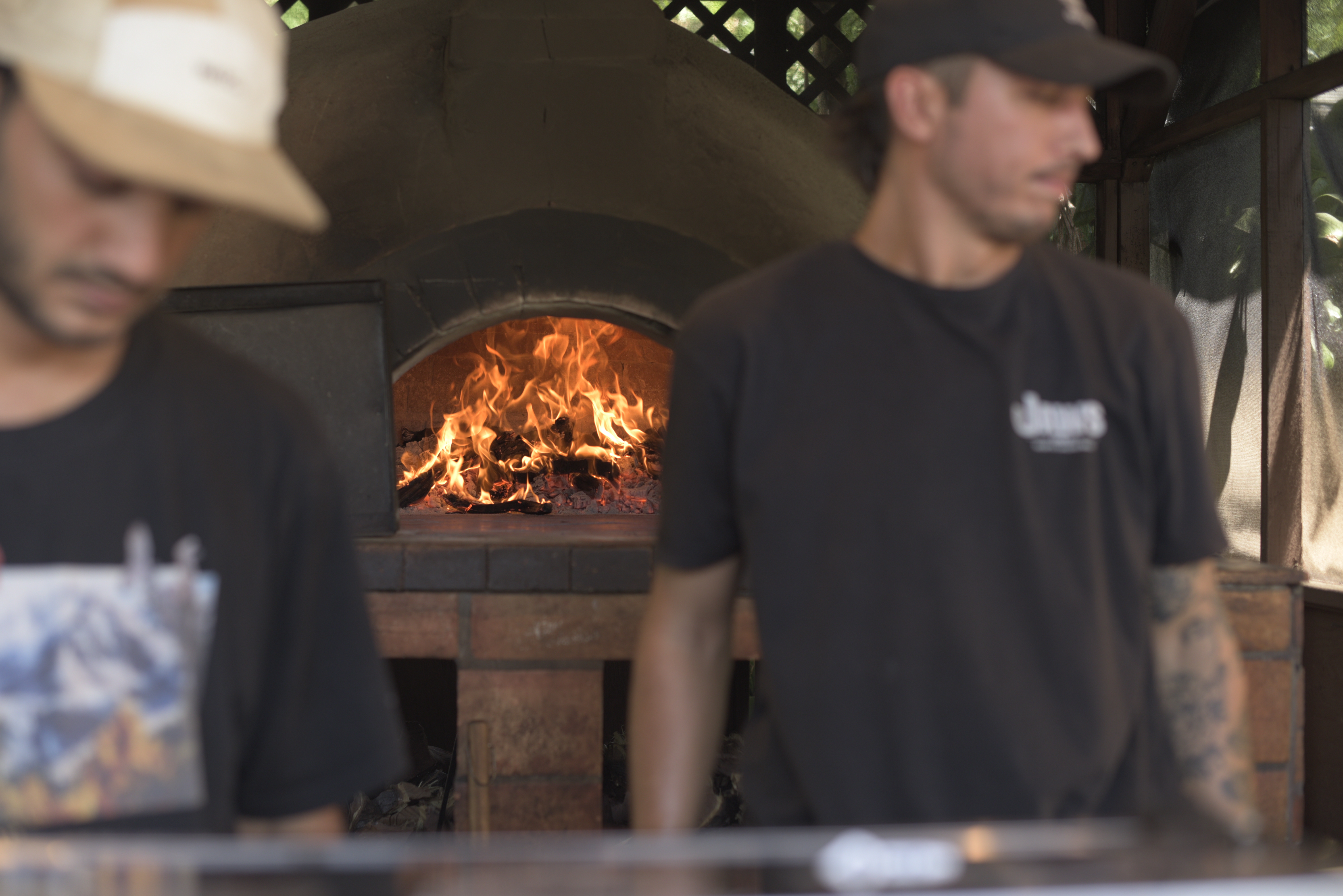 a group of men standing in front of a fire oven