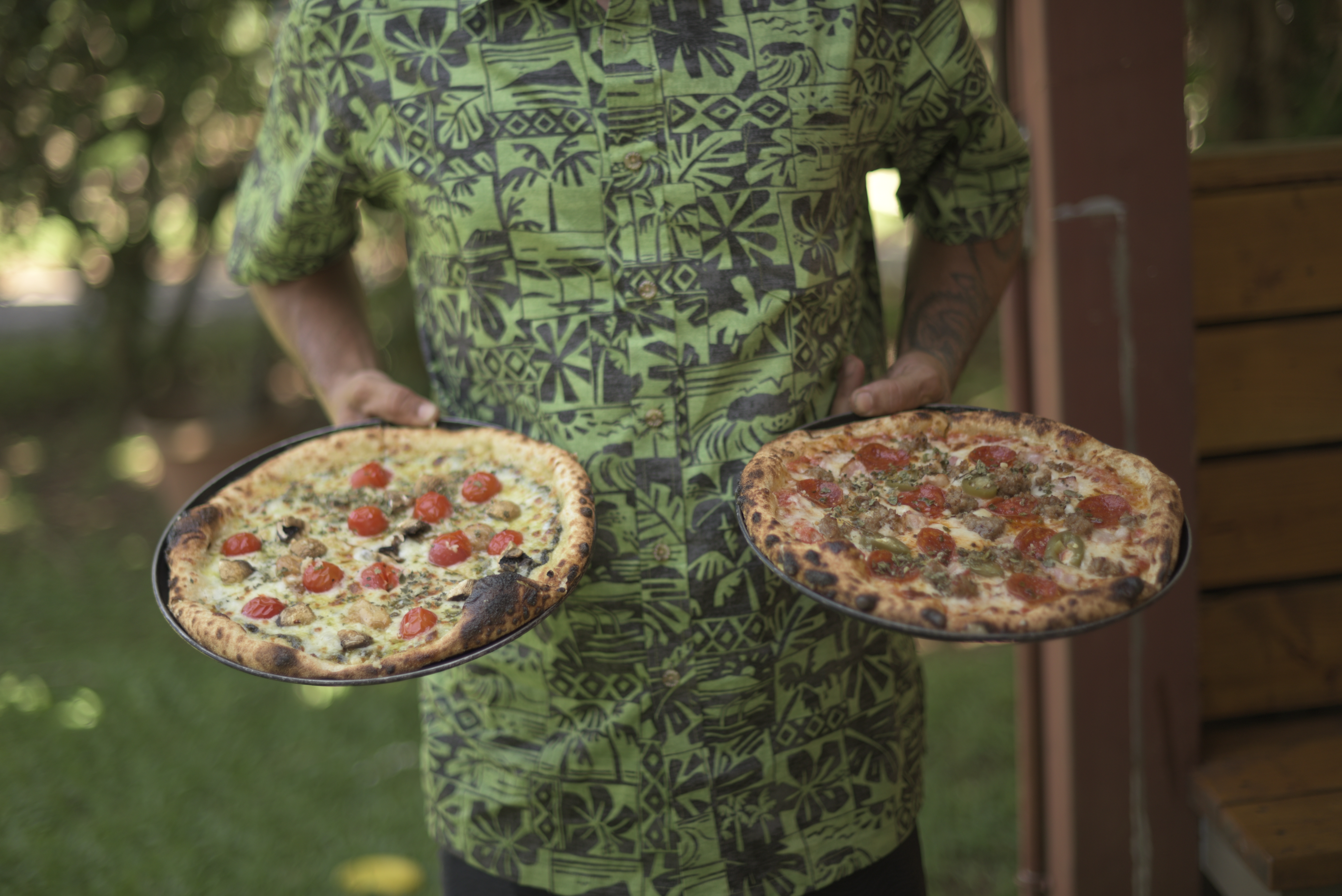 a person holding two pizzas