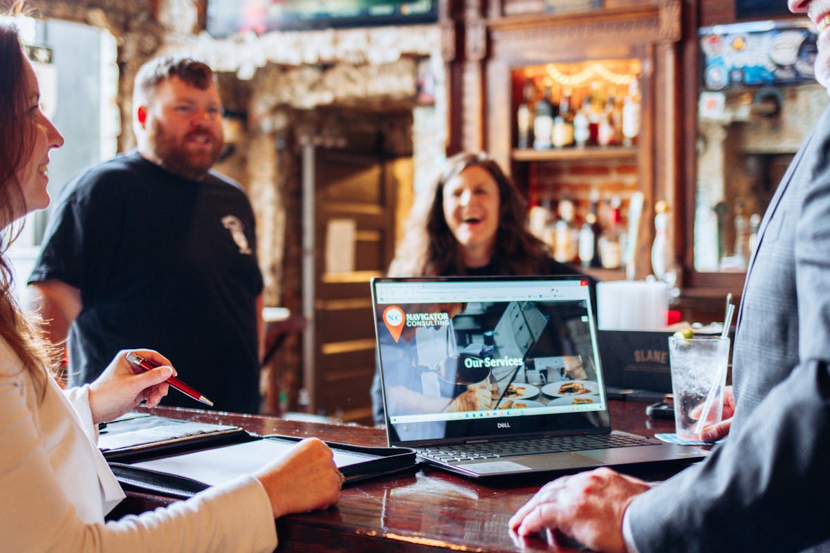 a group of people sitting at a table using a laptop