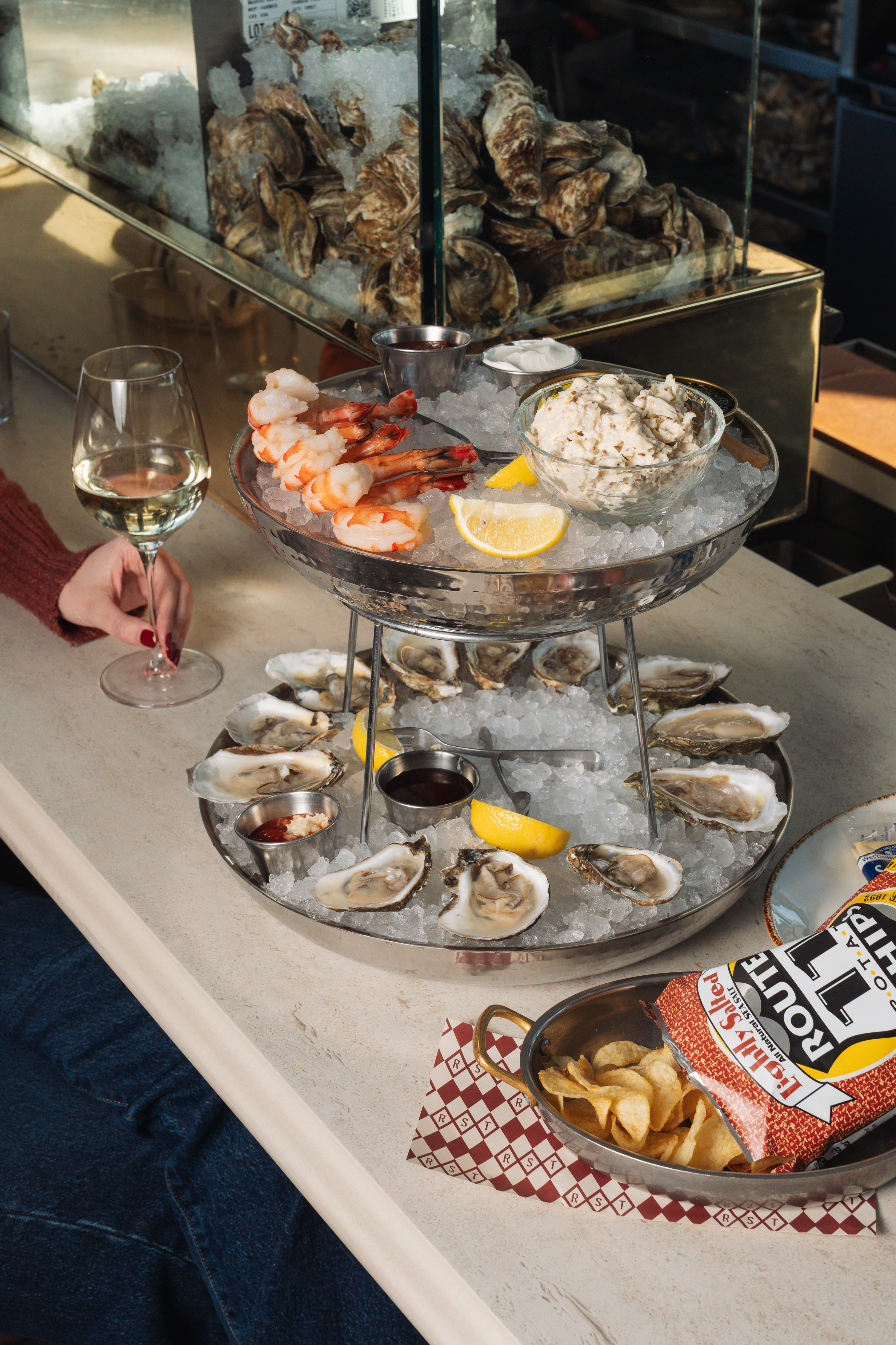 a plate of seafood on ice with a glass of wine