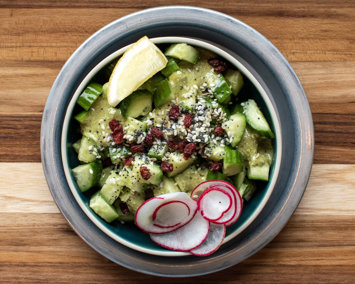 a bowl of salad sitting on top of a wooden table