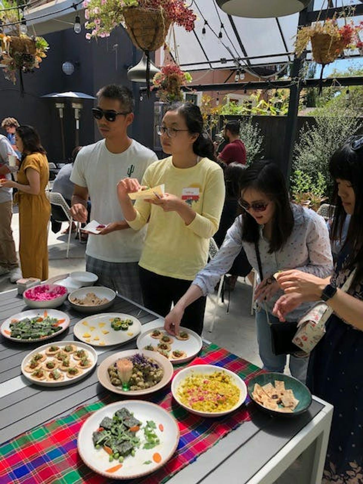 a group of people standing around a table with a plate of food