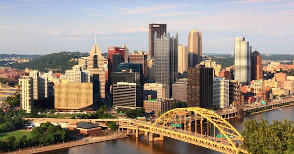 a train crossing a bridge over a river in a city