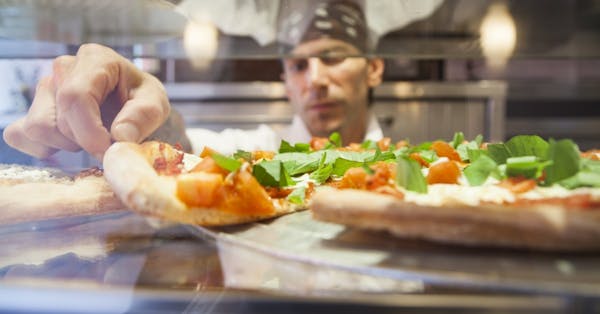 a close up of a person holding a piece of pizza