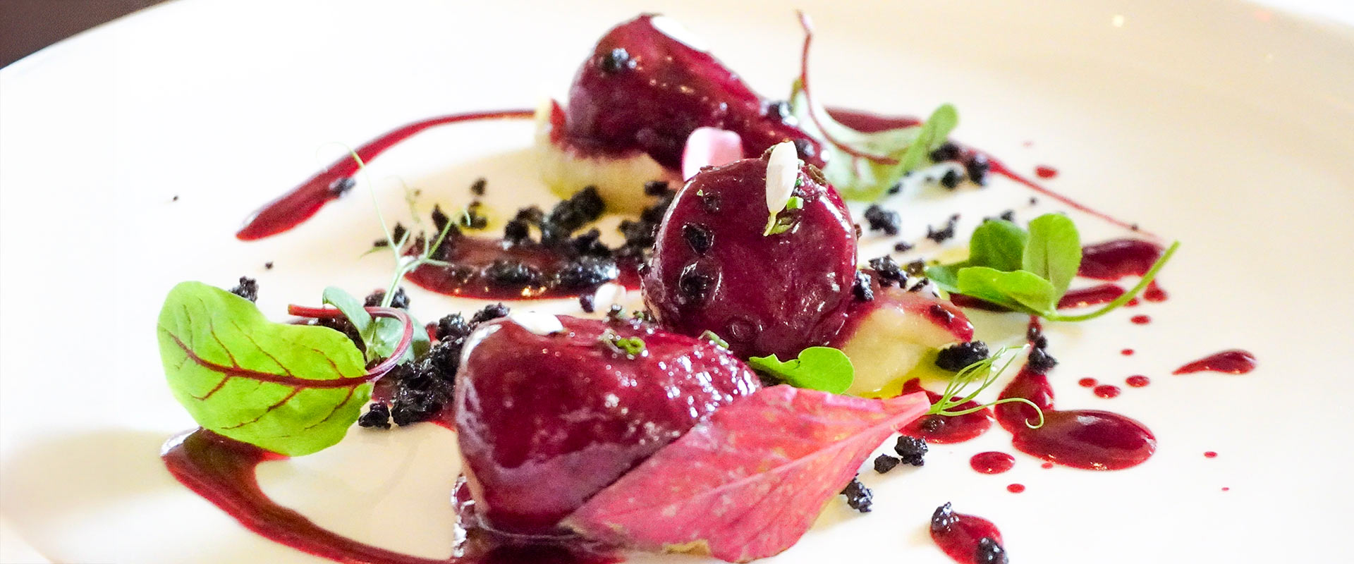 Image of black currant sorbet with white peach on a white dinner plate at The Bocuse Restaurant on CIA’s campus in Hyde Park, NY.