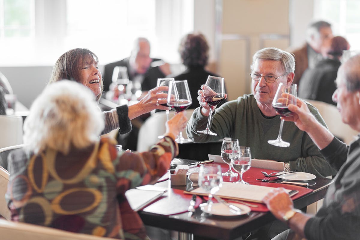 Friends raising their wine glasses for a toast at dinner at the Bocuse Restaurant, Hyde Park, NY.