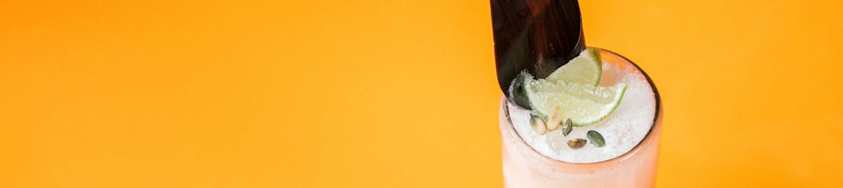 a close up of a drink with ann orange background