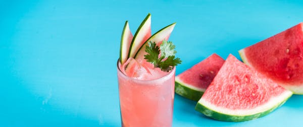 a close up of a drink with watermelon slices next to it