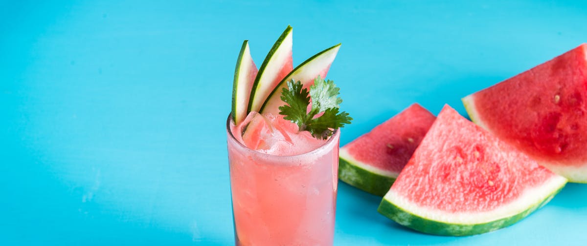 a close up of a drink with watermelon slices next to it