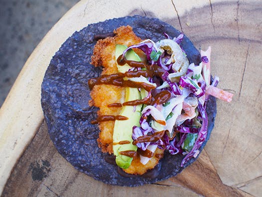 a blue tortilla taco sitting on top of a wooden cutting board