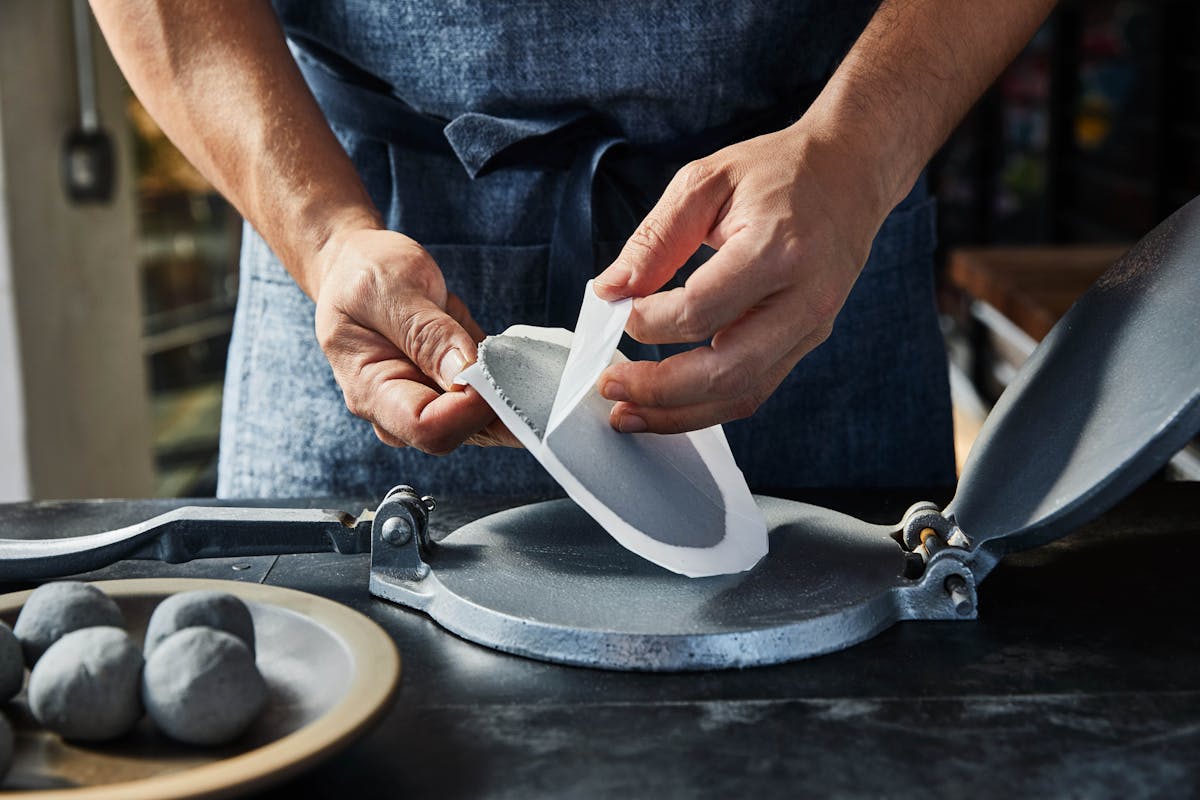 a person making a blue tortilla 