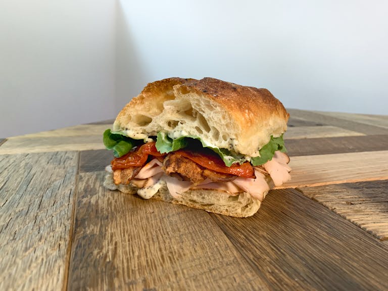 a turkey club sandwich sitting on top of a wooden table