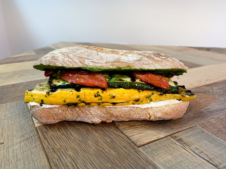 a grilled market vegetable sandwich sitting on top of a wooden table