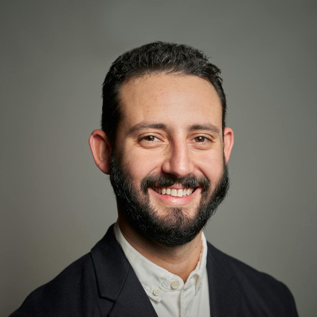 a man wearing a suit and tie smiling and looking at the camera