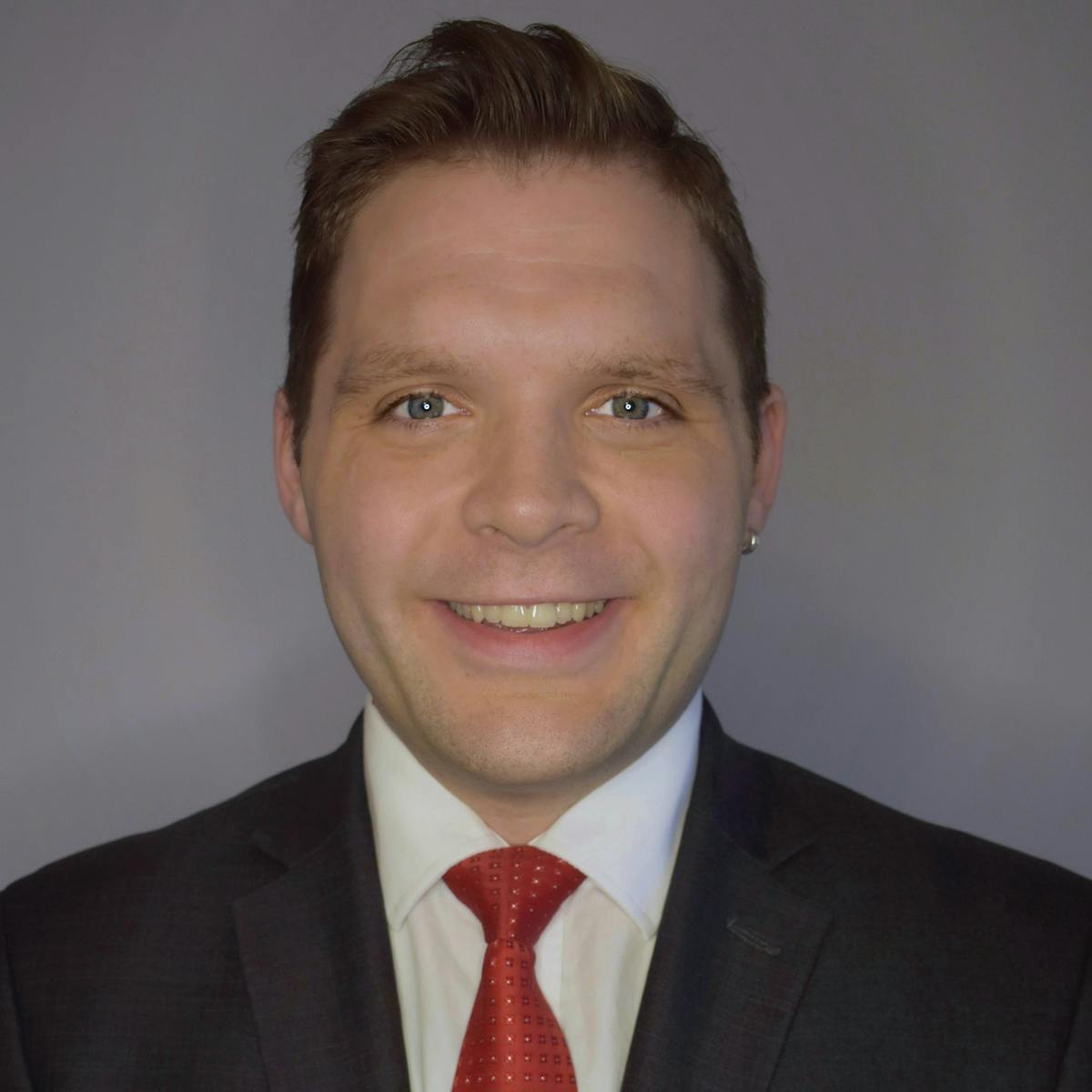 a man wearing a suit and tie smiling at the camera