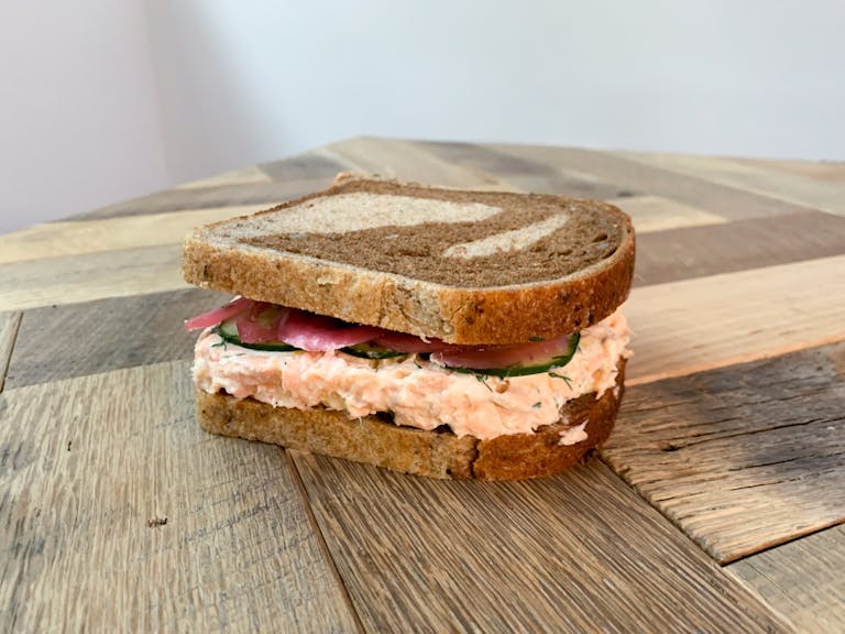 a Salmon Rillettes sandwich sitting on top of a wooden cutting board