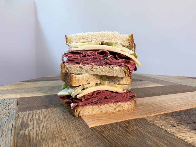 a sandwich sitting on top of a wooden cutting board with a cake