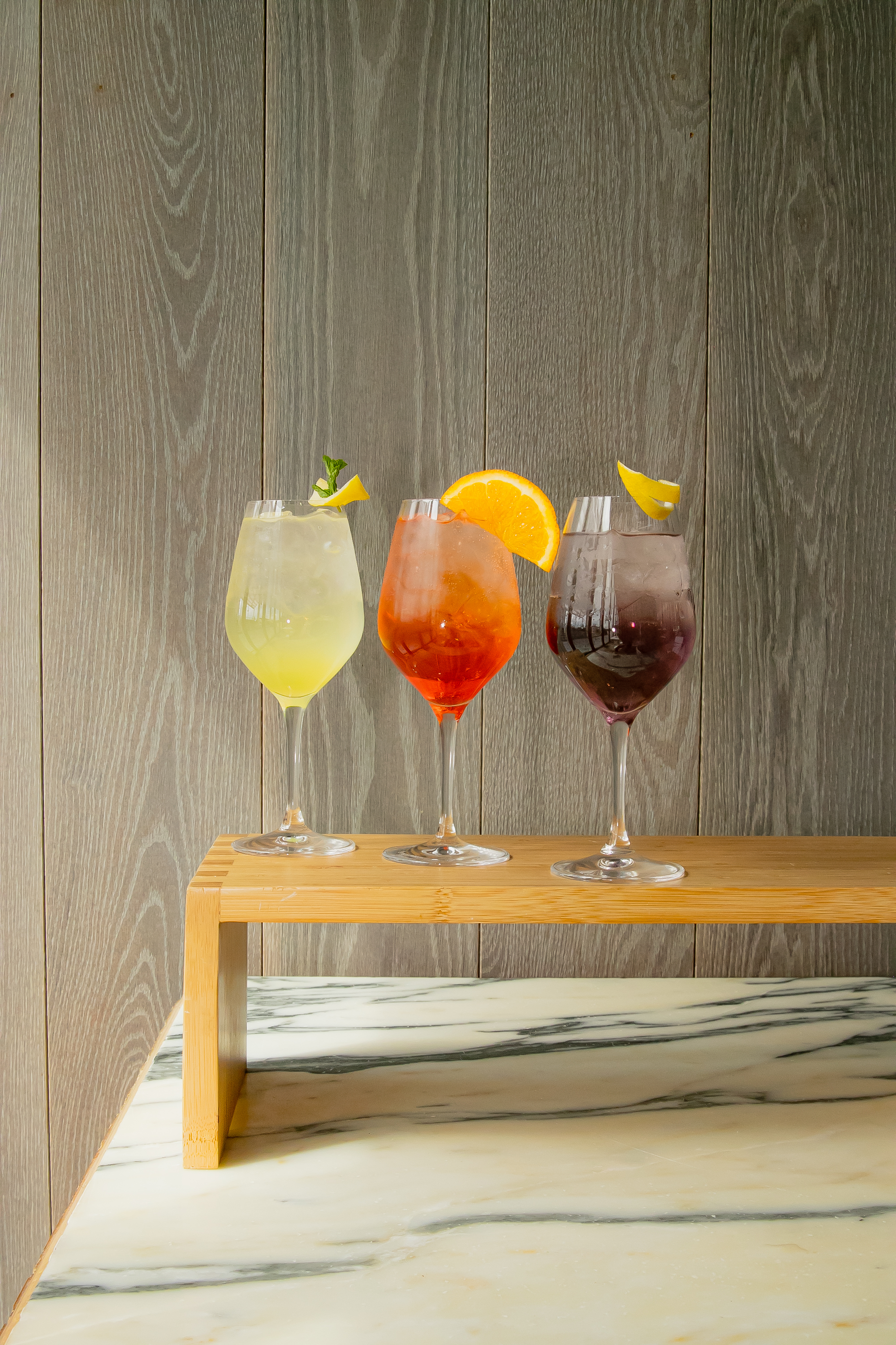 a group of wine glasses with different colored drinks on a wood table