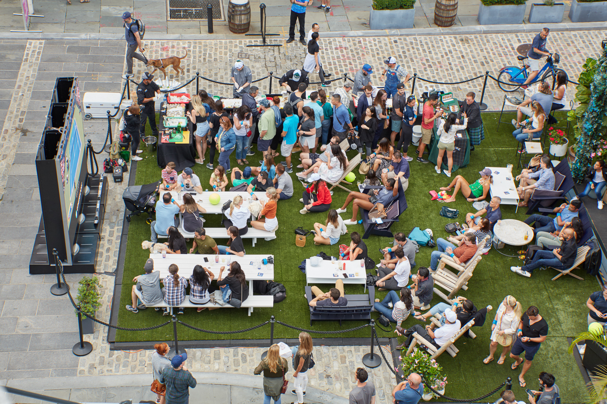 a large group of people gather on an astroturf lawn outdoors