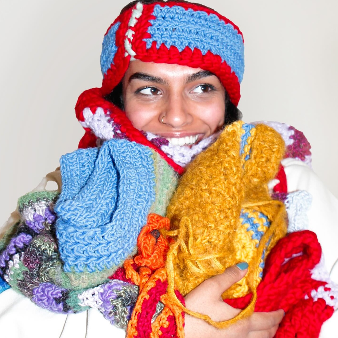 a woman holding and wearing a variety of knit projects