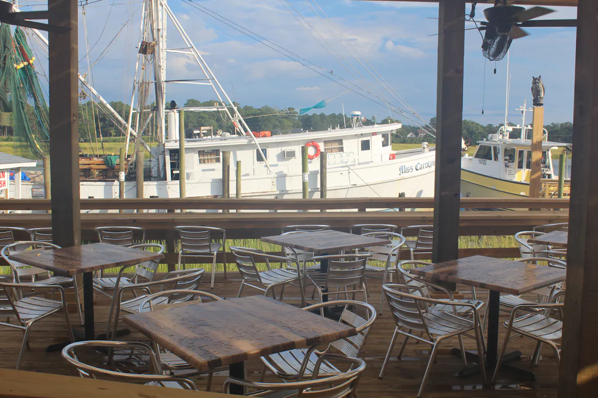 a deck with tables and chairs in front of a boat