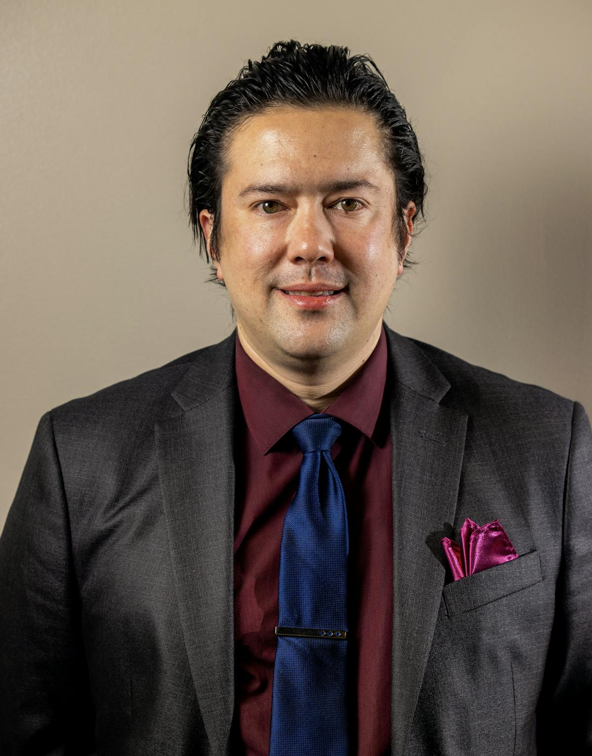 a man wearing a suit and tie smiling at the camera