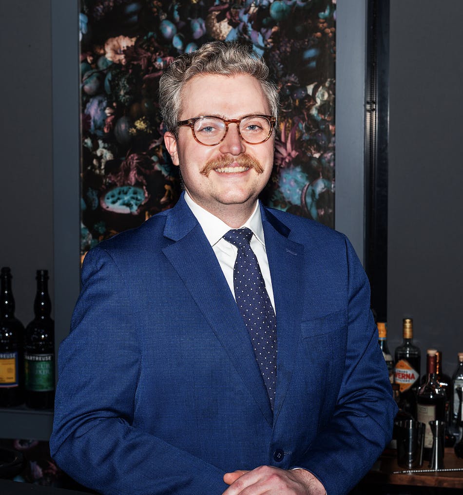 a man wearing a suit and tie smiling at the camera