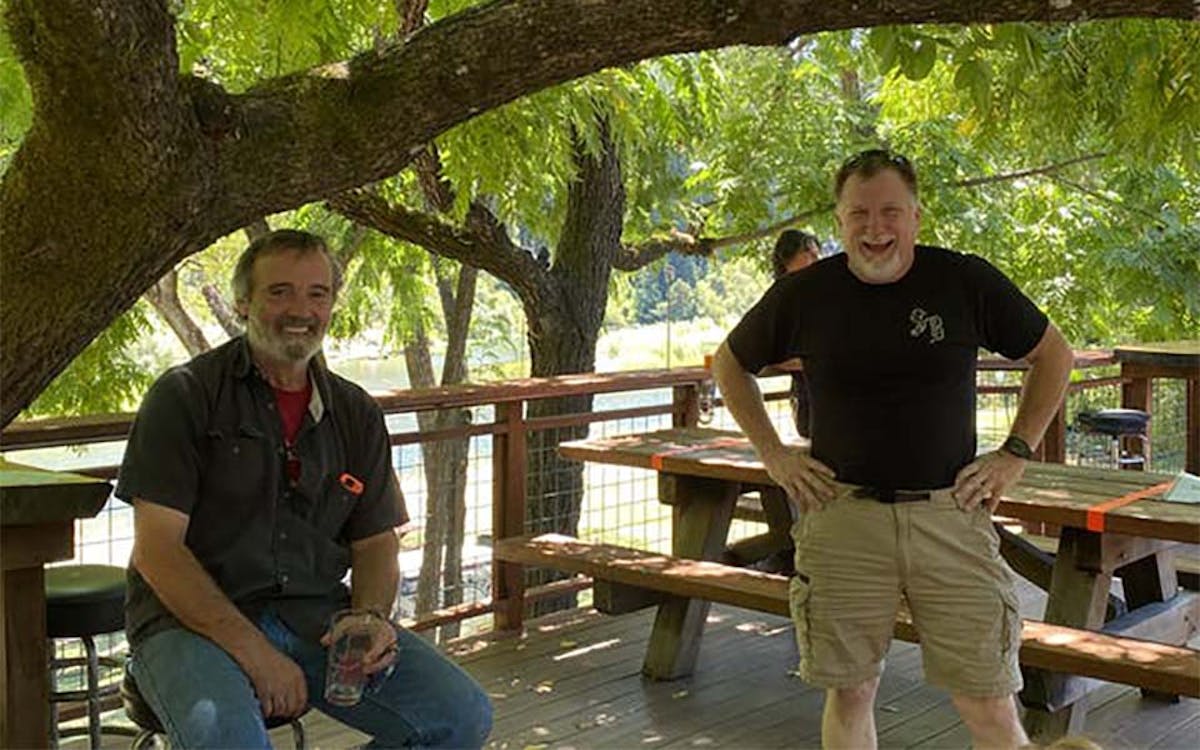 a group of people sitting on a bench next to a tree