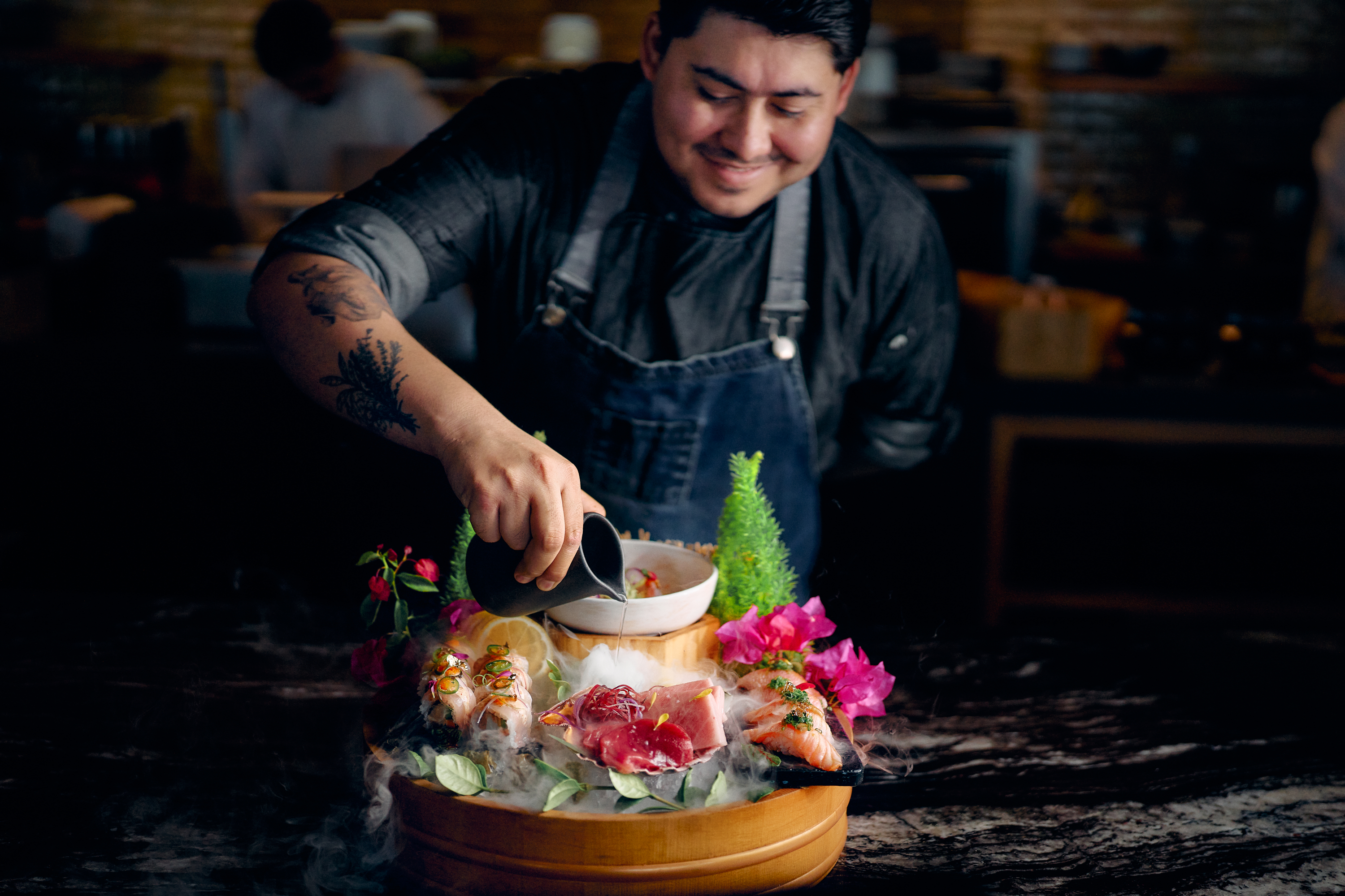 Chef preparing an elaborate seafood dish with dry‑ice mist at Cayao