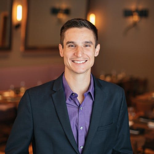 a man wearing a suit and tie smiling at the camera
