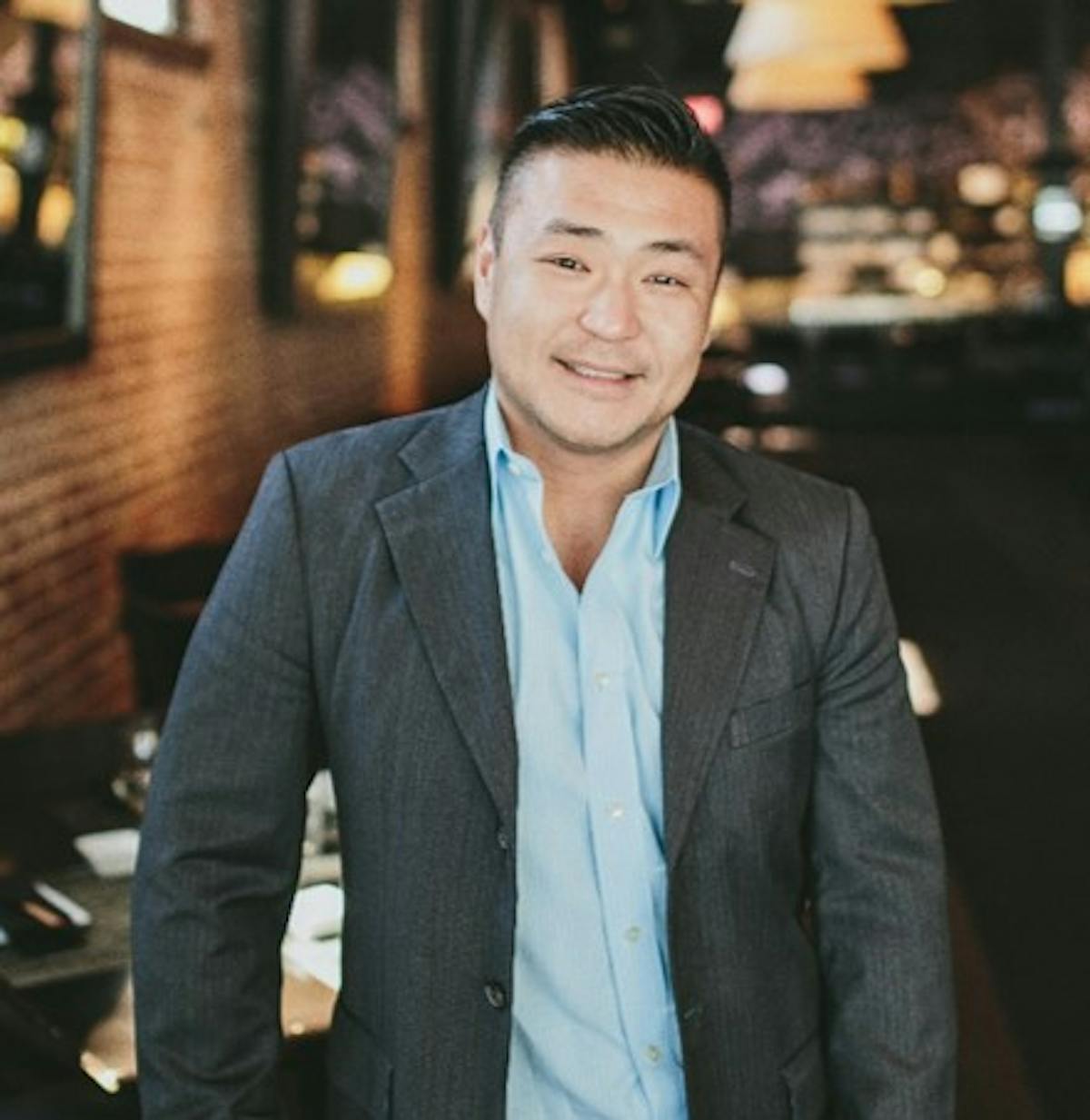 a man wearing a suit and tie smiling for the camera