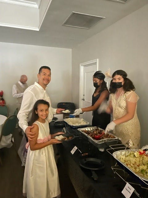 a group of people standing in a kitchen preparing food