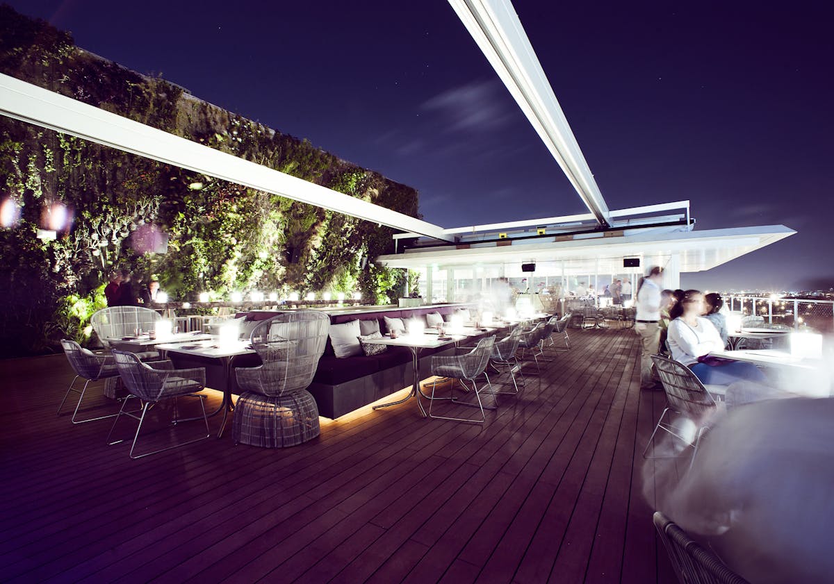 an extensive patio at night filled with lighten up tables and chairs
